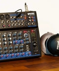 12 Channel Bluetooth Audio Mixer With USB Playback And FX For Bands, Podcasters, DJs, and Live Sound Pros on wooden table