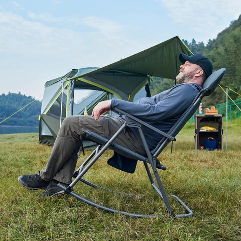 Person relaxing outdoors in oversized folding rocking camping chair with padded high back, portable rocker, supports up to 400 lbs, blue.
