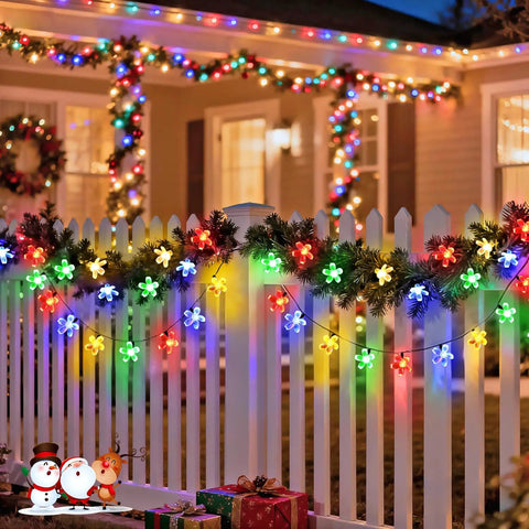 Outdoor Solar Cherry Blossom String Lights 2 Pack, 30.6 Ft Each, 50 LED Multicolor Flower Lights draped on a white garden fence at night.