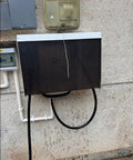 Super Tough Outdoor Electric Charger Rain Cover Hella Rugged Weatherproof Box mounted on a wall with rain droplets.