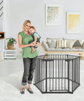 Mother with child beside Oxford 3 In 1 Play Yard Baby Gate And Fireplace Fence For A 151 Inch Extra Wide Barrier in a living room.