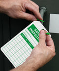 Hands attaching Top Shelf Safety Inspection Tags Paired With Adjustable Wire Ties For Quick Equipment Checks And Job Site Warning Labels.
