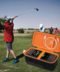 Rugged Carrying Case For Wingman HD GPS Speaker open on golf course with player swinging, showing black and orange protective interior.