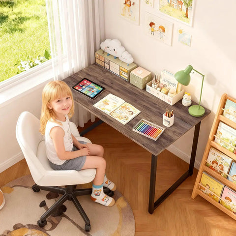 Child sitting at a Compact 32 Inch Computer Desk In Brown With Steel Frame And Adjustable Feet, in home study area.