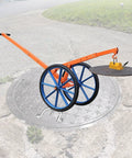Heavy Duty Steel Manhole Cover Lifter Cart With Magnetic Skid Rollers And 27 Inch All Terrain Wheels shown lifting a manhole cover.