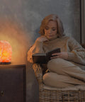 Woman reading by Three Pack Natural Pink Himalayan Salt Lamp With Dimmer Cord And Light Bulb Six To Eight Inch Tall Salt Rock Lamp With Wood Base Hand Crafted 100 Percent Authentic Great For Home Office And Bedroom Decor Cozy Vibe Mood Lighting