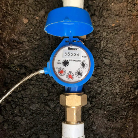 Top view of a blue One Inch Irrigation Flow Meter For Sprinklers With Real Time Water Usage Data And Leak Alerts installed underground.