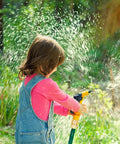 Child playing with water hose in garden, showcasing Eight Piece Three Quarter Inch Garden Hose Quick Connectors Set Made From Solid Brass No Leak