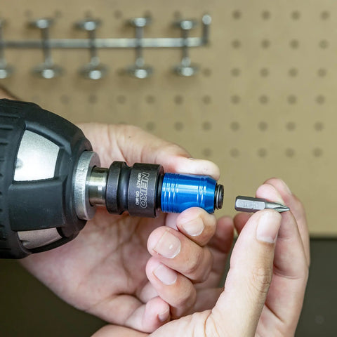 Person holding Impact Wrench Adapter One Half Inch Drive To One Quarter Inch Hex Converter with Quick Change Chuck near a drill bit.