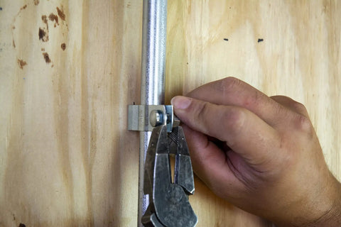 Person securing conduit with Bulk Nail Plate One And A Half Inch By Two And A Half Inch Tough As Nails Durable Steel Connector Plate