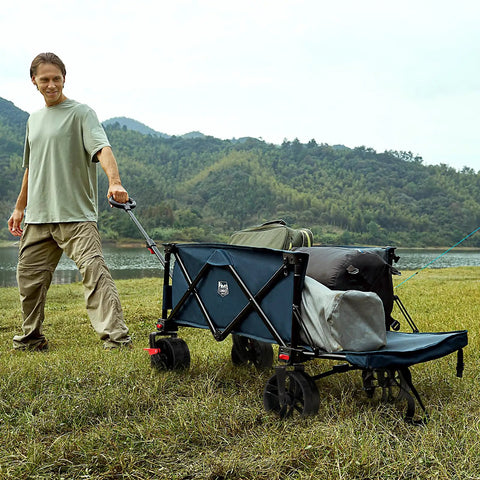 Heavy Duty Collapsible Wagon With Tailgate And Brakes All Terrain Big Wheel Cart 250L Foldable Utility Cart For Beach Camping Sand Sports Shopping 300 Lb Capacity Blue being pulled by person on grass with mountains