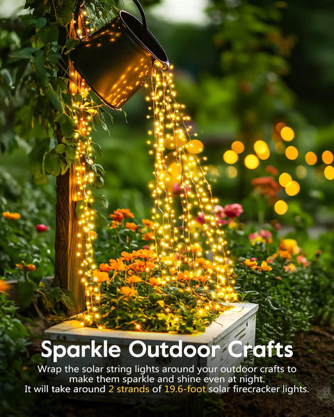 Watering can with 120LED 10Ft Solar Fairy Lights Outdoor Waterproof With 8 Modes IP65 Firecracker Twinkle String Lights cascading over flowers at night.