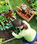 Gardener using Heavy Duty Garden Tools Set With Basket, Stainless Steel Hand Tools With Wood Handles, Pruning Shears, Gloves, A Must Have For Budding Gardeners And Pros, Great Gardening Gift For Women And Men, Planting Supplies next to a garden bed