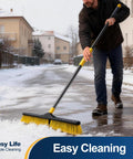 Heavy Duty 24 Inch Push Broom With Adjustable Telescoping Handle Up To 65 Inches clearing snow on a road, with ergonomic grip.