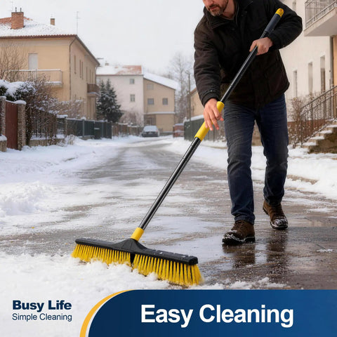 Heavy Duty 24 Inch Push Broom With Adjustable Telescoping Handle Up To 65 Inches clearing snow on a road, with ergonomic grip.