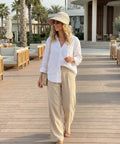 Woman wearing 2-In-1 Women's Sun Visor Hat With Wide Brim Or Zip-Off Top walking on boardwalk, palm trees in background