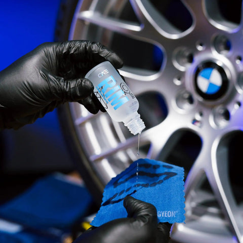 Applying Rim EVO 30ml Ceramic Wheel Coating Kit to blue cloth near silver car rim, high heat resistant up to 1400°F.