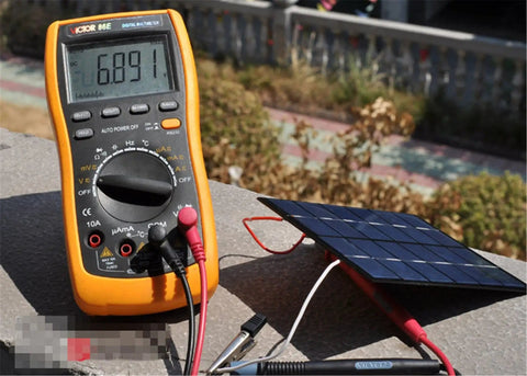 Mini USB Solar Panel Module 2W 6V With Blocking Diode, connected to a multimeter outdoors, showcasing charging capability