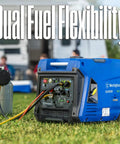 Blue dual fuel 5000 peak watt inverter generator with remote start on grass, featuring RV-ready outlet and USB ports, connected to propane tank.