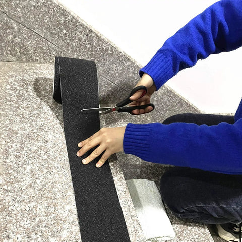 Person cutting Heavy Duty 4 Inch Anti Slip Tape 35 Ft Roll With 80 Grit Friction For Indoor And Outdoor Stairs Traction Non Skid Waterproof Grip Tape Black