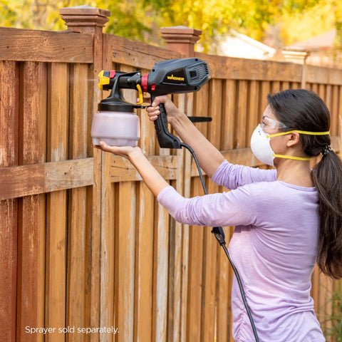 Woman using iSpray Front End Nozzle For HVLP Sprayers Broad Interior And Exterior Coverage With Unthinned Coatings on fence