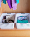 Two white baskets with contoured handles in a cabinet, part of Large Ultra Storage Baskets Pack Of 6 For Closet, Cabinet, And Pantry Organization