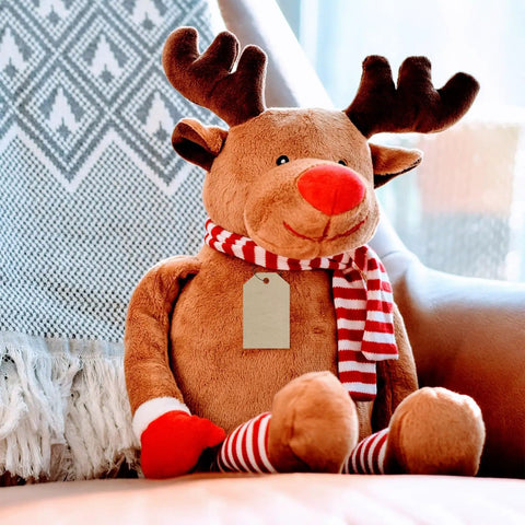Stuffed reindeer with red and white scarf on a chair, showing retail hang tag attached with plastic fasteners.
