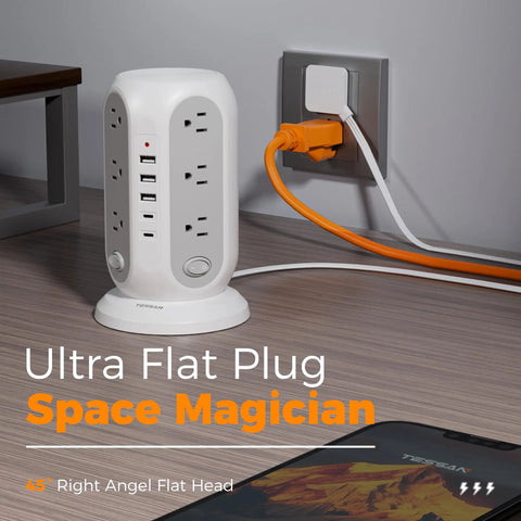 Tower Power Strip With 12 Outlets And 5 USB Ports, Including 2 USB C, Individual Switches, 10 Ft Flat Extension Cord, 1250W Surge Protector, All In One Charging Station For Office Or Dorm, Grey displayed on desk next to wall plug, right angle view.