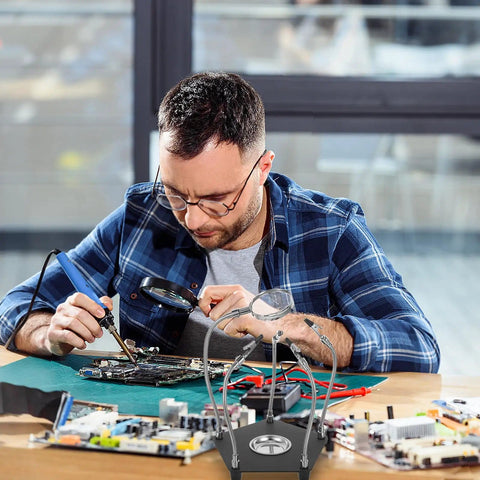 Man using Adjustable Soldering Station Helping Hand With Flexible Arms And PCB Holder for electronics repair on a desk
