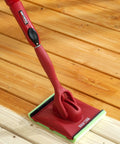 Deck Stain Pad With Groove Tool For Even Coverage On Flat Surfaces And Between Boards with red handle on wood deck
