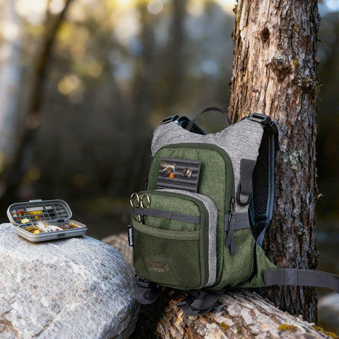 Fly Fishing Chest Pack With Workstation And Quick Release Lightweight Tackle Bag outdoors by a tree and rocks.