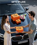 Man and woman exchanging gift boxes on car hood with flowers