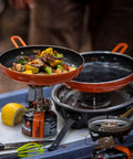 Summit Skillet Nonstick Camping Cookware with vegetables cooking on backpacking stove, orange ceramic-coated pan visible.