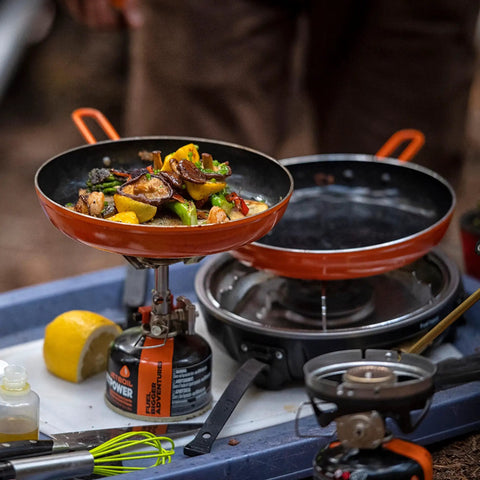 Summit Skillet Nonstick Camping Cookware with vegetables cooking on backpacking stove, orange ceramic-coated pan visible.