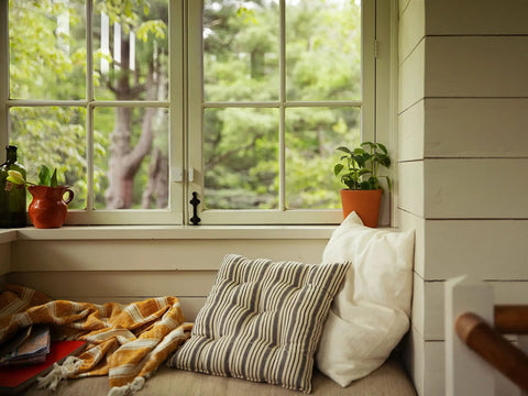 Cozy window nook with pillows and plants, showcasing peaceful indoor setting. Entry Sensor Pack of 4 for Doors and Windows available.