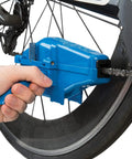 Hand using CM25 Professional Chain Scrubber Tool For Bike Chains Shop Grade With Four Sided Scrubbing Action Fast Thorough Cleaning Durable Blue Finish