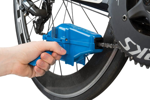 Hand using CM25 Professional Chain Scrubber Tool For Bike Chains Shop Grade With Four Sided Scrubbing Action Fast Thorough Cleaning Durable Blue Finish