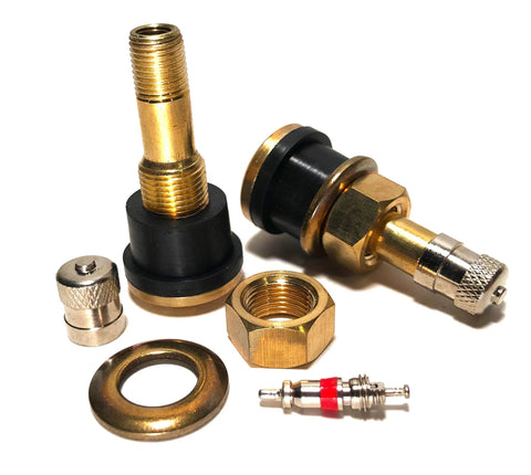 Close-up of brass tubeless tire valve stems with clamp-in bases and assorted accessories for trucks and buses.