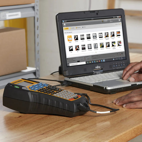 Straight Up Heavy Duty Jobsite Computer Connected Label Maker With Rechargeable Battery connected to laptop on a workspace.