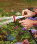 Person using Heavy Duty Garden Hose Nozzle With Five Adjustable Spray Patterns For Lawn And Garden Jet Shower Mist Sweep Fill Thumb Trigger Control Durable Metal Construction Ergonomic Grip Built Tough For Everyday Watering in garden
