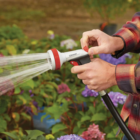 Person using Heavy Duty Garden Hose Nozzle With Five Adjustable Spray Patterns For Lawn And Garden Jet Shower Mist Sweep Fill Thumb Trigger Control Durable Metal Construction Ergonomic Grip Built Tough For Everyday Watering in garden
