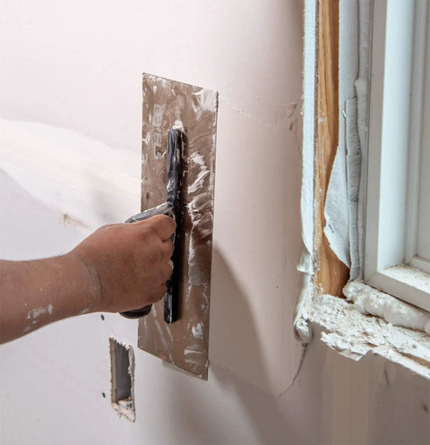 Flex Drywall Curved Trowel 12-Inch By 4.75-Inch With 0.5mm Blade in use on drywall near a window edge