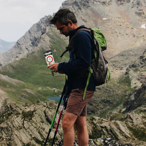 Man using Ultra Lightweight Hiking Compass With Luminous Dial Scale Ruler And Mirror in mountain landscape