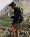 Man with hiking backpack using Orienteering Hiking Compass With Luminous Dial For Backcountry Navigation in mountains