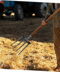 Steel Garden Fork Replacement Head Four Tine Heavy Duty Digging Fork handling straw in a farm setting