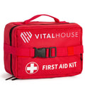 Front view of red VitalHouse first aid kit bag with top handle, buckle strap, and FIRST AID KIT label.