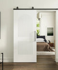 Silky Smooth Two Panel Sliding Barn Door With Reeded Arched White Primed Finish For Modern Farmhouse Room Divider in home setting