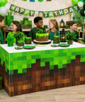 Kids celebrating around a table decorated with Two Pack Pixel Miner Party Table Skirts With Classic Green And Brown Block Pattern.