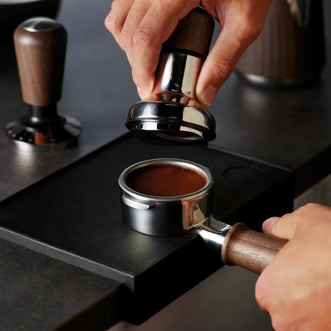 Pro 58 Mm Espresso Powder Distributor With Tough Walnut Handle And Stainless Steel Tines, leveling coffee grounds in a portafilter.