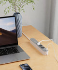 Slick Black Smart Power Strip With WiFi App Control, Heavy Duty Surge Protector, Built In USB Charging Ports on a desk with laptop.